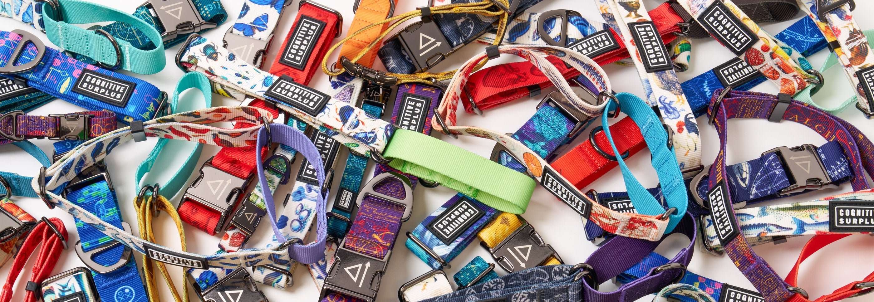 A selection of colorful dog collars with various patterns, each featuring a black and white "Corrine Surplus" label, arranged in diagonal rows.