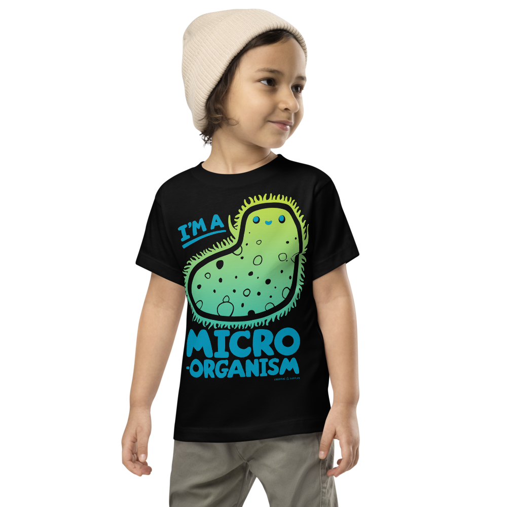 A child wearing a beige beanie and a black T-shirt with a cartoon microorganism and the text &quot;I&#39;m a Micro Organism.