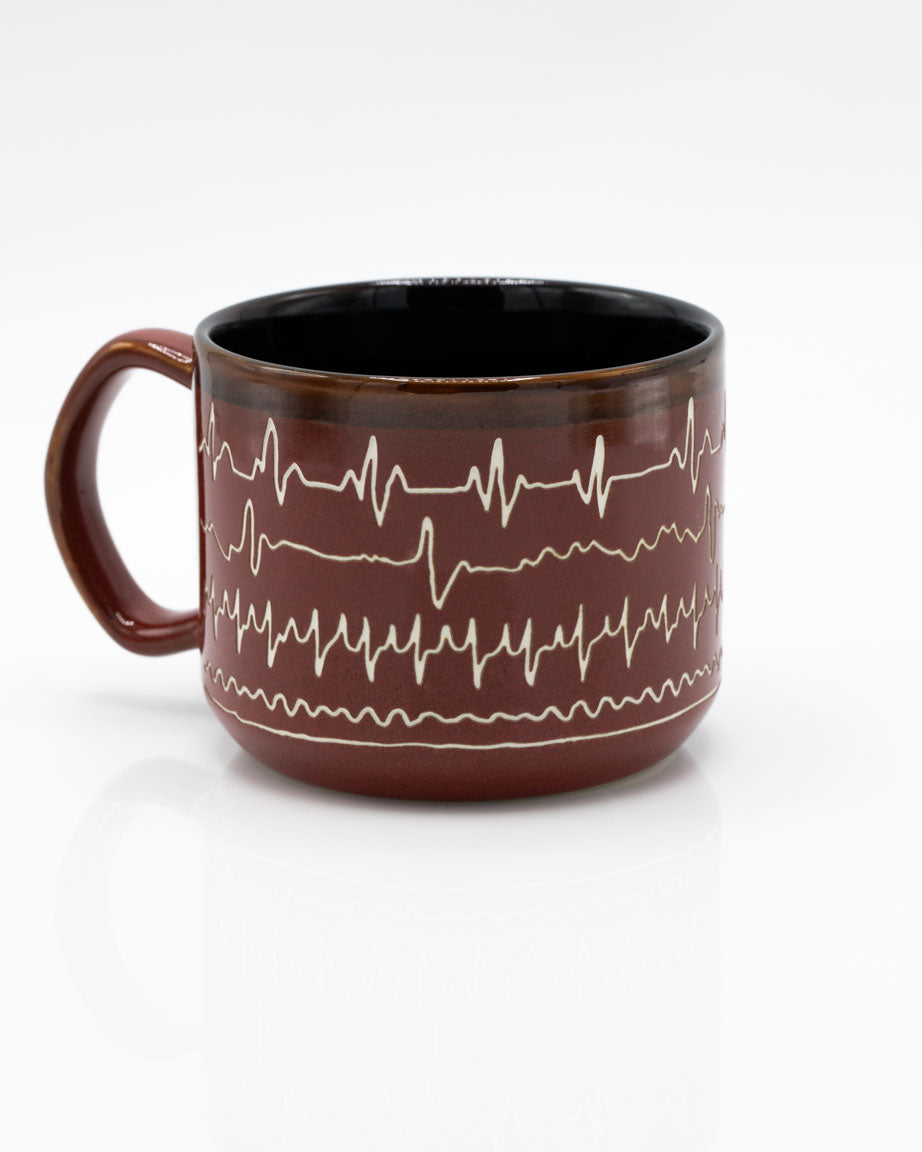 A Heartbeat Hand Carved 15 oz Ceramic Mug with an ecg pattern on it, made by Cognitive Surplus.