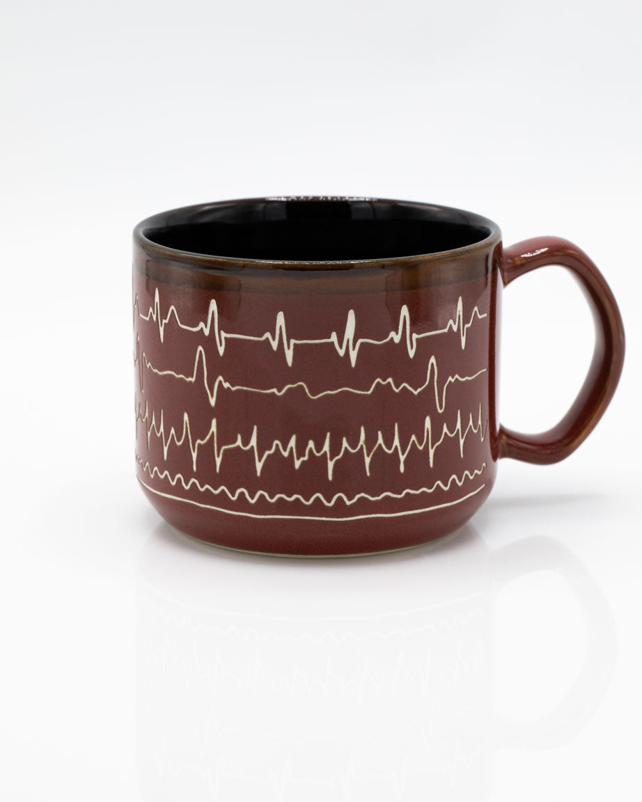 A Cognitive Surplus Heartbeat Hand Carved 15 oz Ceramic Mug with a heartbeat pattern on it.