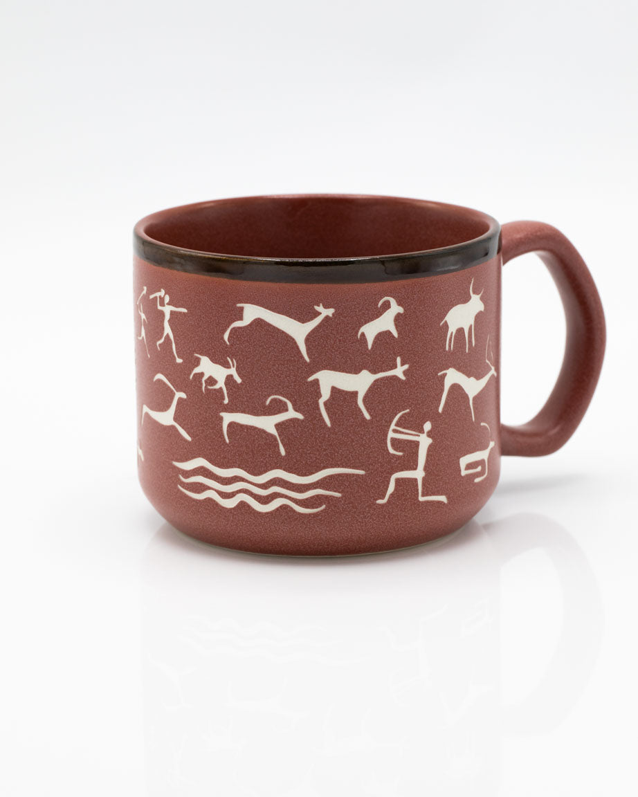A Cave Paintings Hand Carved 15 oz Ceramic Mug by Cognitive Surplus with white and brown designs on it.