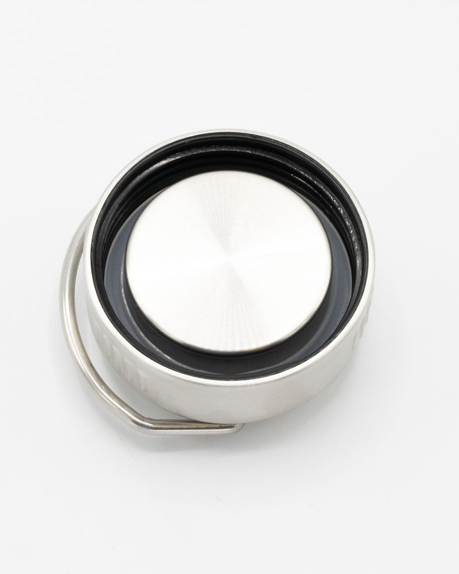 A silver button on a white surface.