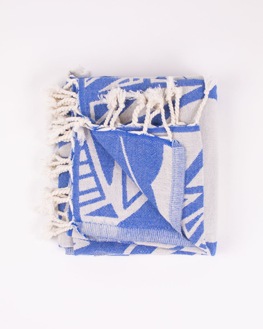 A blue and white Cognitive Surplus Cloud Watching Turkish Towel with tassels.