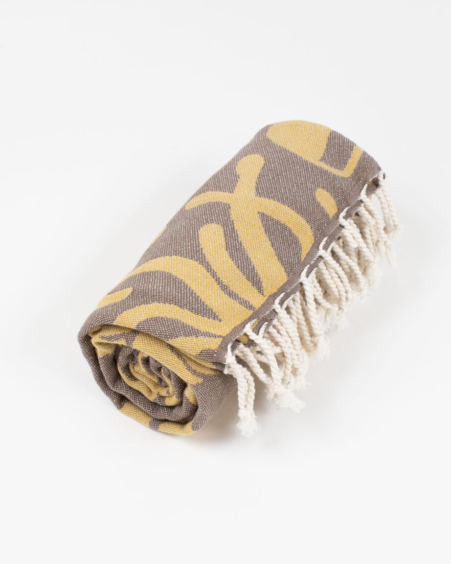 A Tide Pool Turkish Towel by Cognitive Surplus, a yellow and grey towel with fringes.
