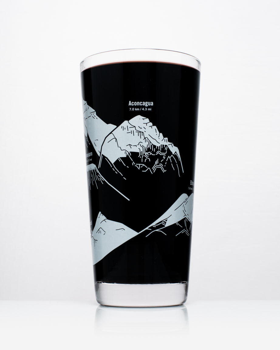 A black and white SECONDS: Mountain Peaks of the World Beer Glass (12 oz) with mountains on it by Cognitive Surplus.