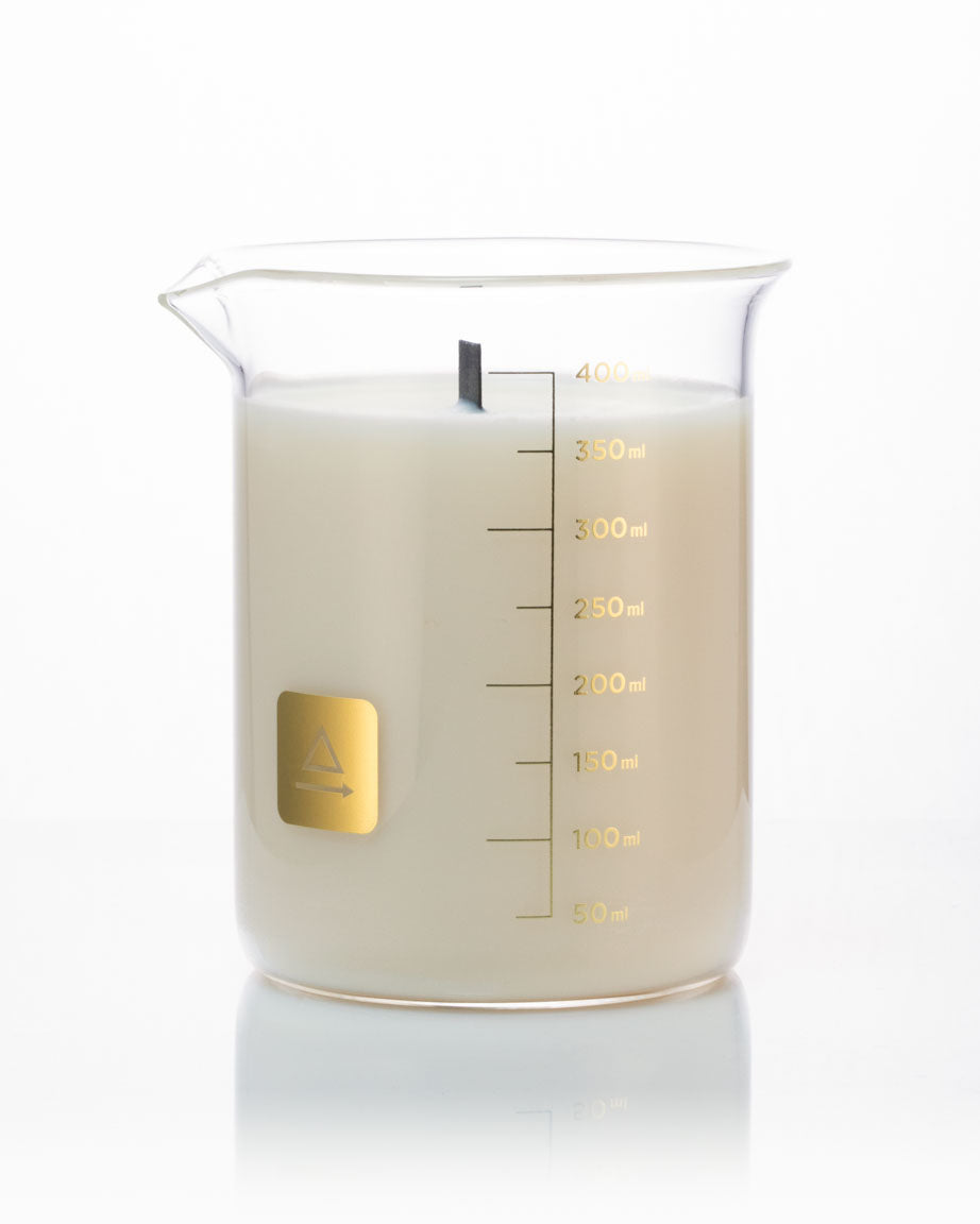 A Cognitive Surplus Beaker Candle with a measuring cup on a white background.