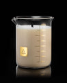 A Beaker Candle in a beaker with a gold label on it by Cognitive Surplus.