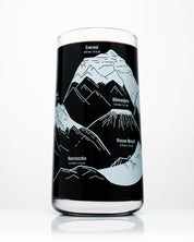 A Mountain Peaks of the World Drinking Glass by Cognitive Surplus with a map of the mountains on it.