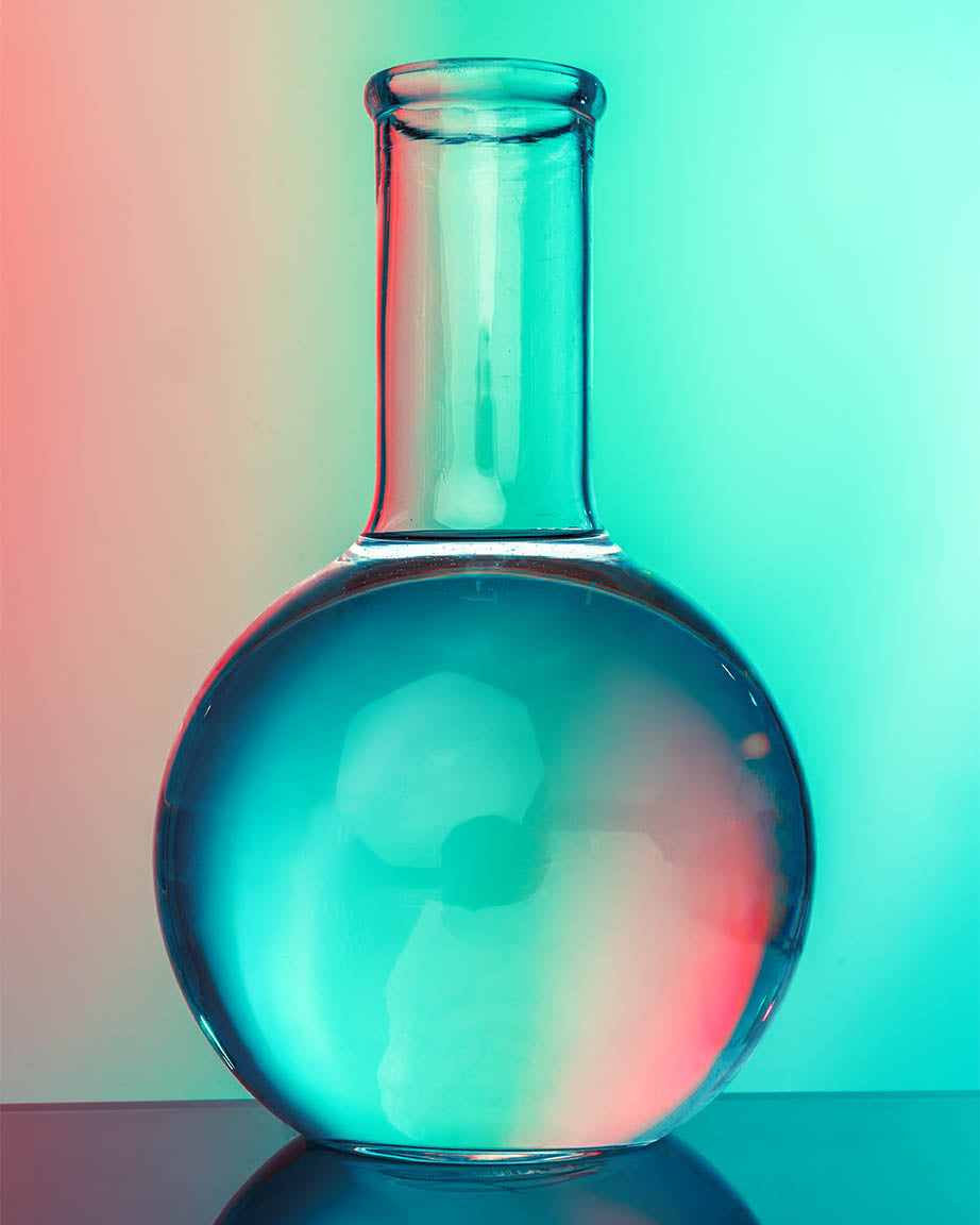 A Mysteries of the Laboratory Field Pack flask sitting on a table with a colorful background. Brand Name: Cognitive Surplus.