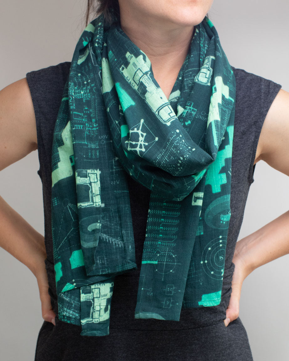 A woman wearing a Cognitive Surplus Electronics Engineering Scarf with a green and black design.