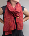 A woman wearing a Cognitive Surplus Equations That Changed the World Scarf with geometric designs on it.