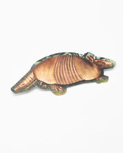 A Cognitive Surplus Armadillo Sticker is laying on a white surface.