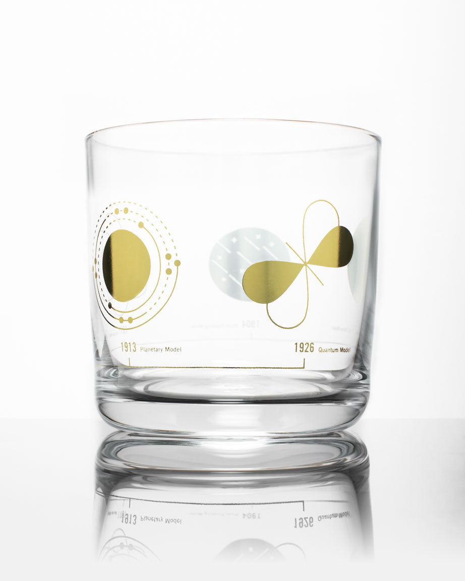 An Atomic Models Whiskey Glass with a gold and yellow design on it, by Cognitive Surplus.