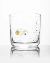 A Solar System Whiskey Glass with a gold and silver design on it by Cognitive Surplus.