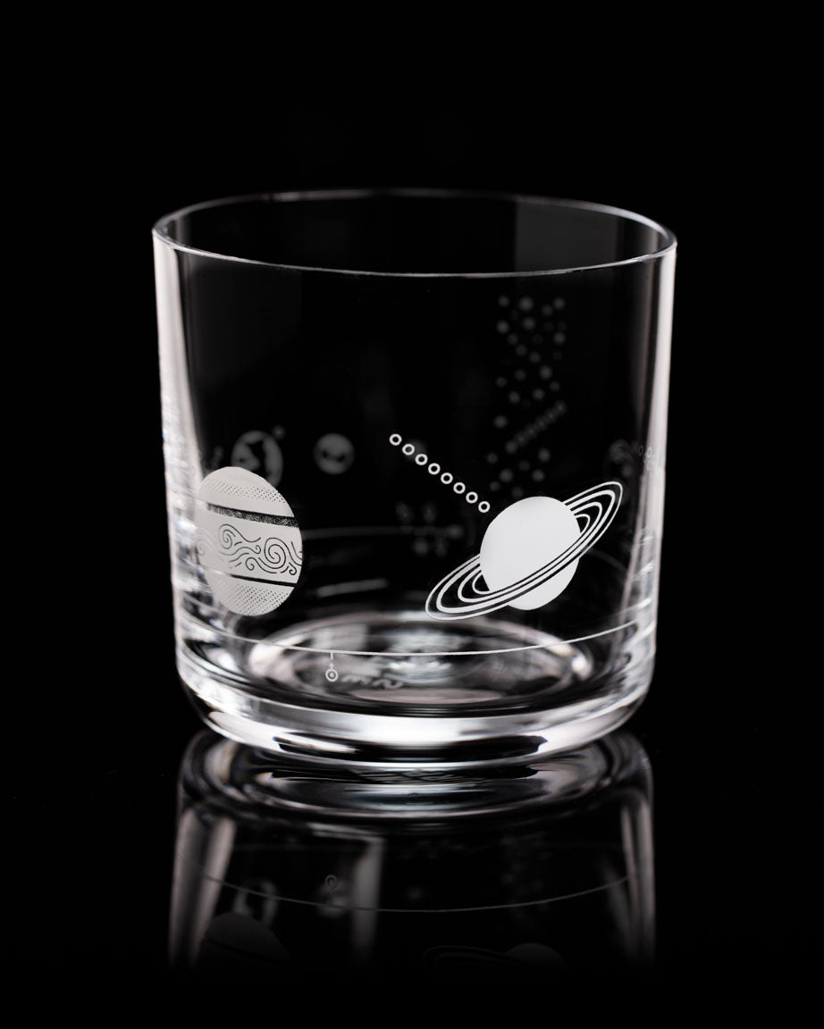 A SECONDS: Solar System Whiskey Glass by Cognitive Surplus is on a black surface.